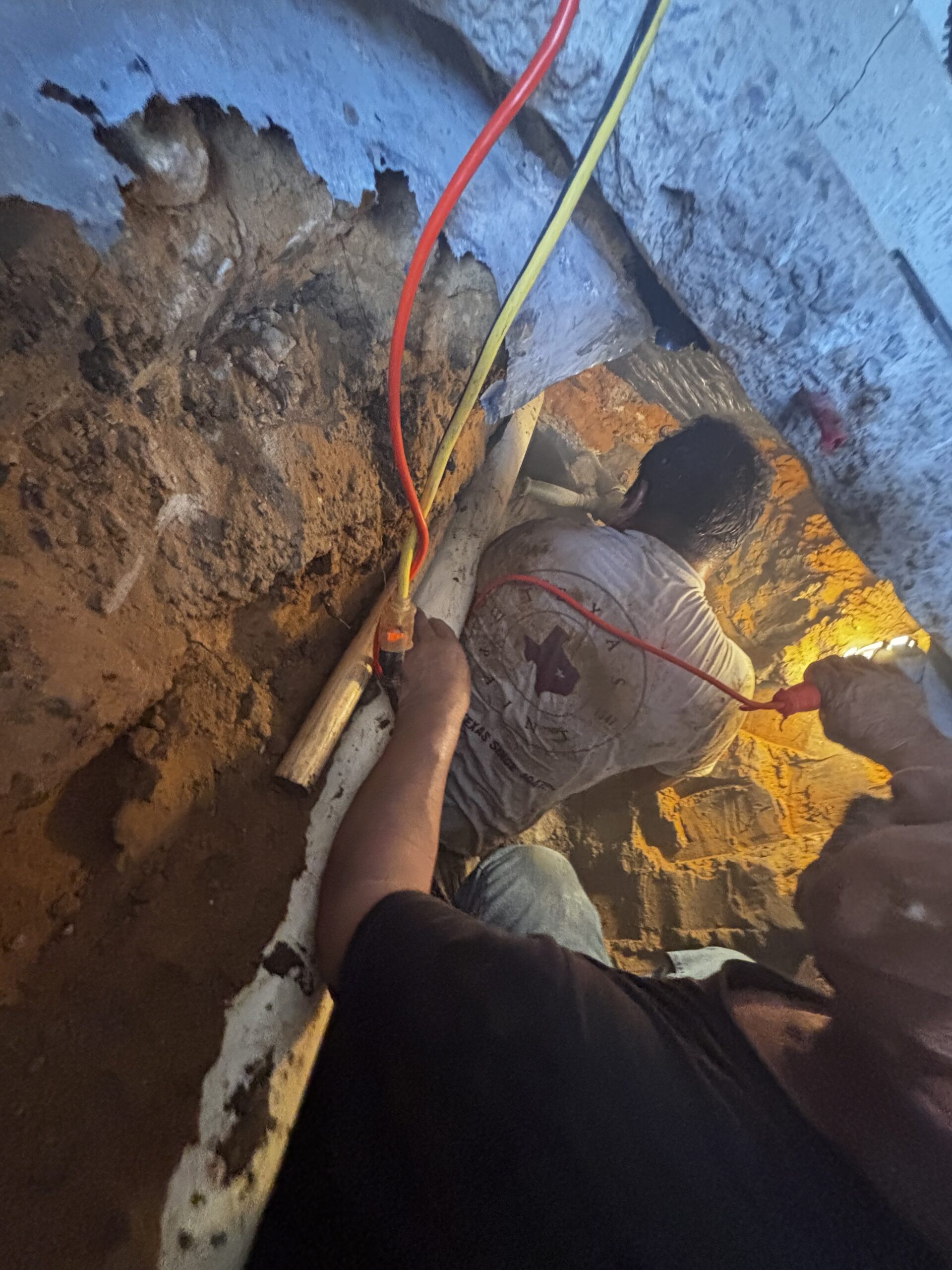 Technicians working inside garage trench during sewer line replacement in The Colony Texas