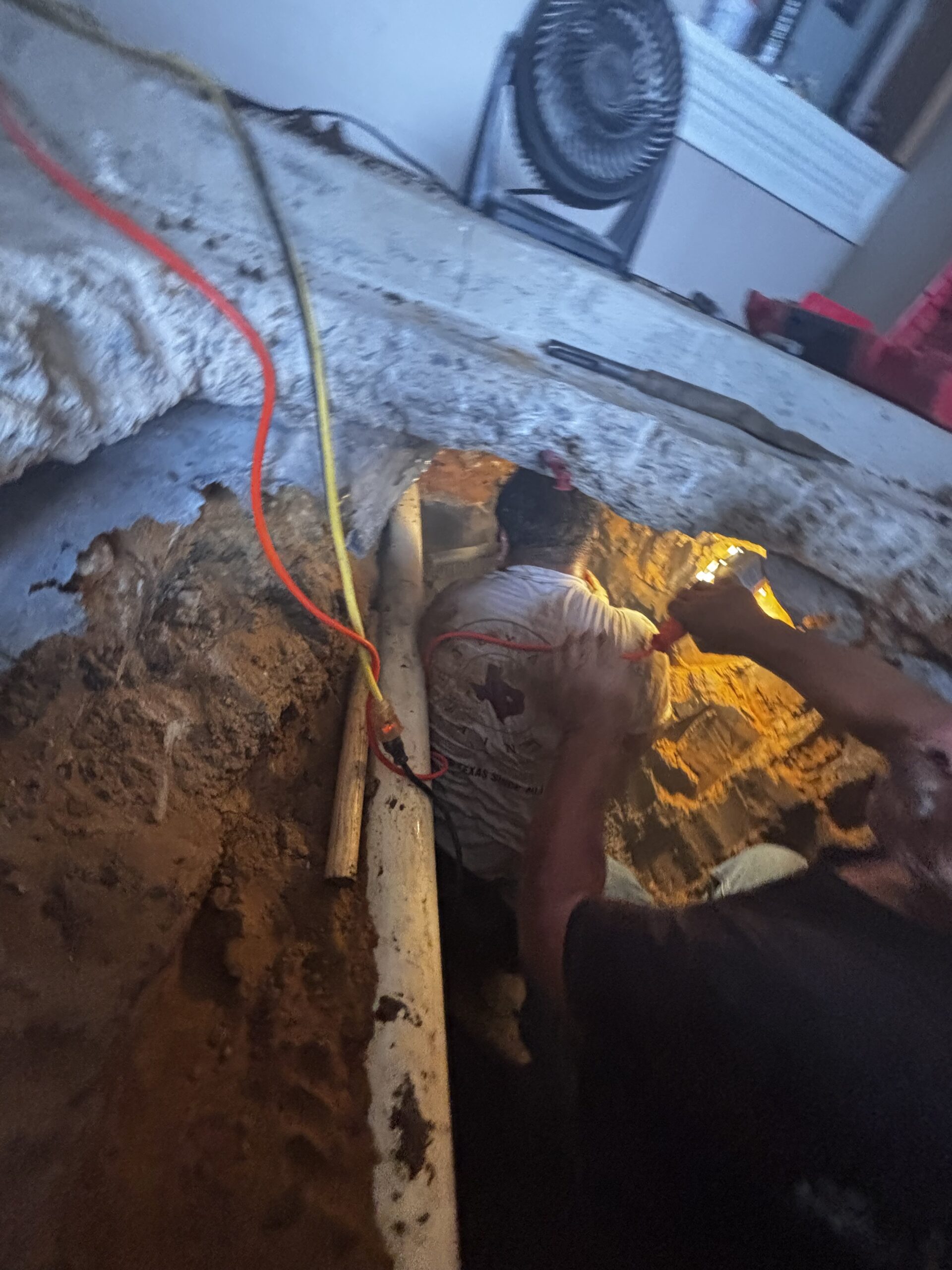 Close view of garage sewer trench and exposed pipe under slab