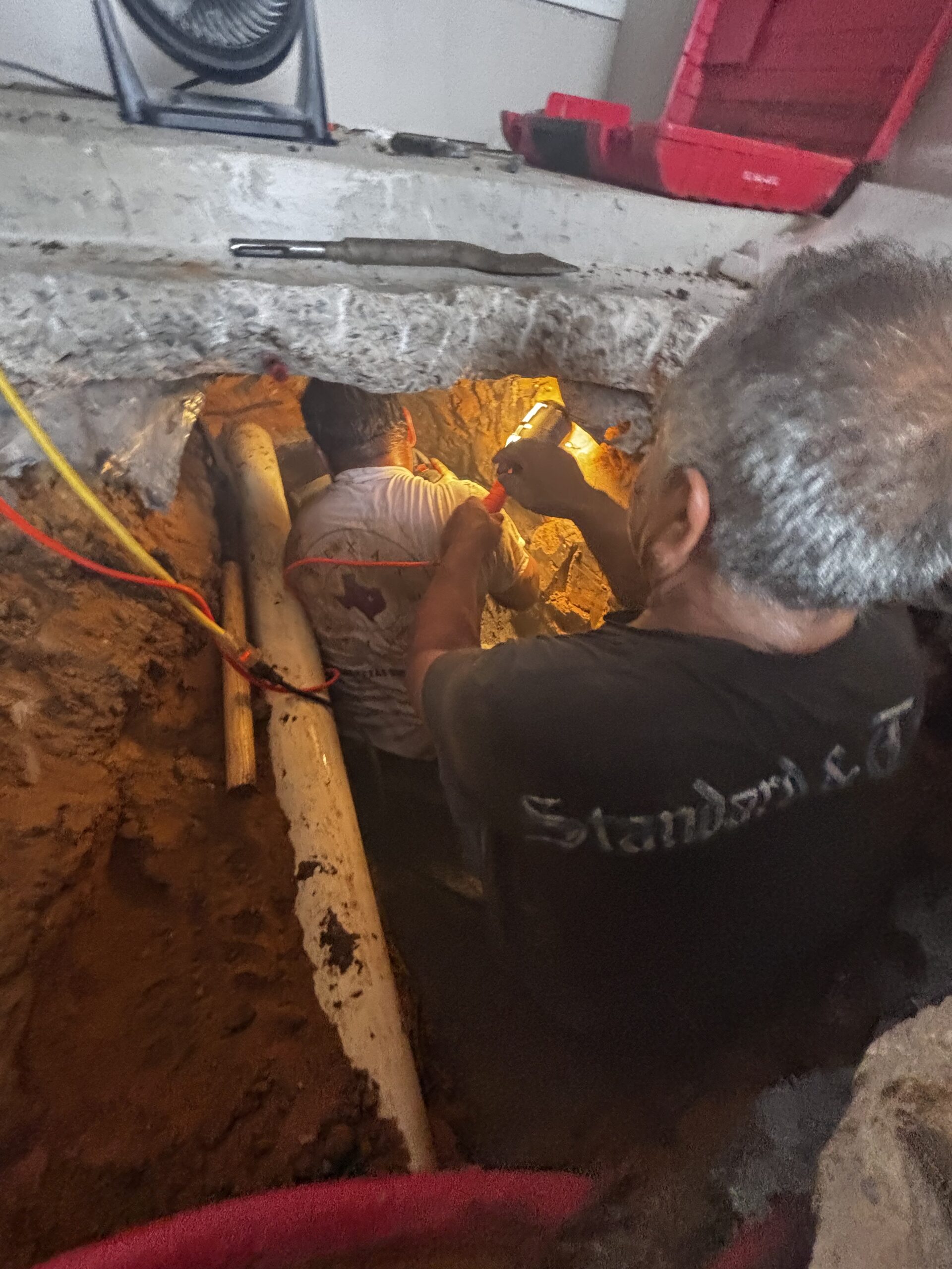 Under slab sewer trench with technicians correcting slope issue after foundation repair