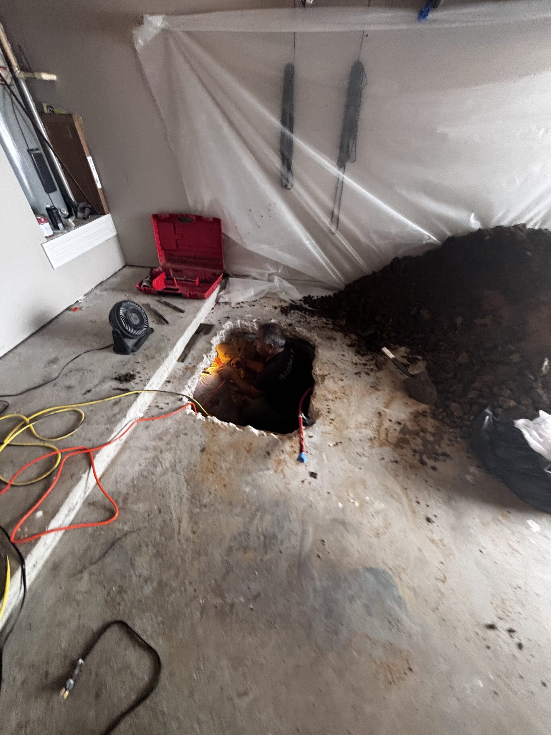 Garage floor sewer line replacement project with excavation and containment